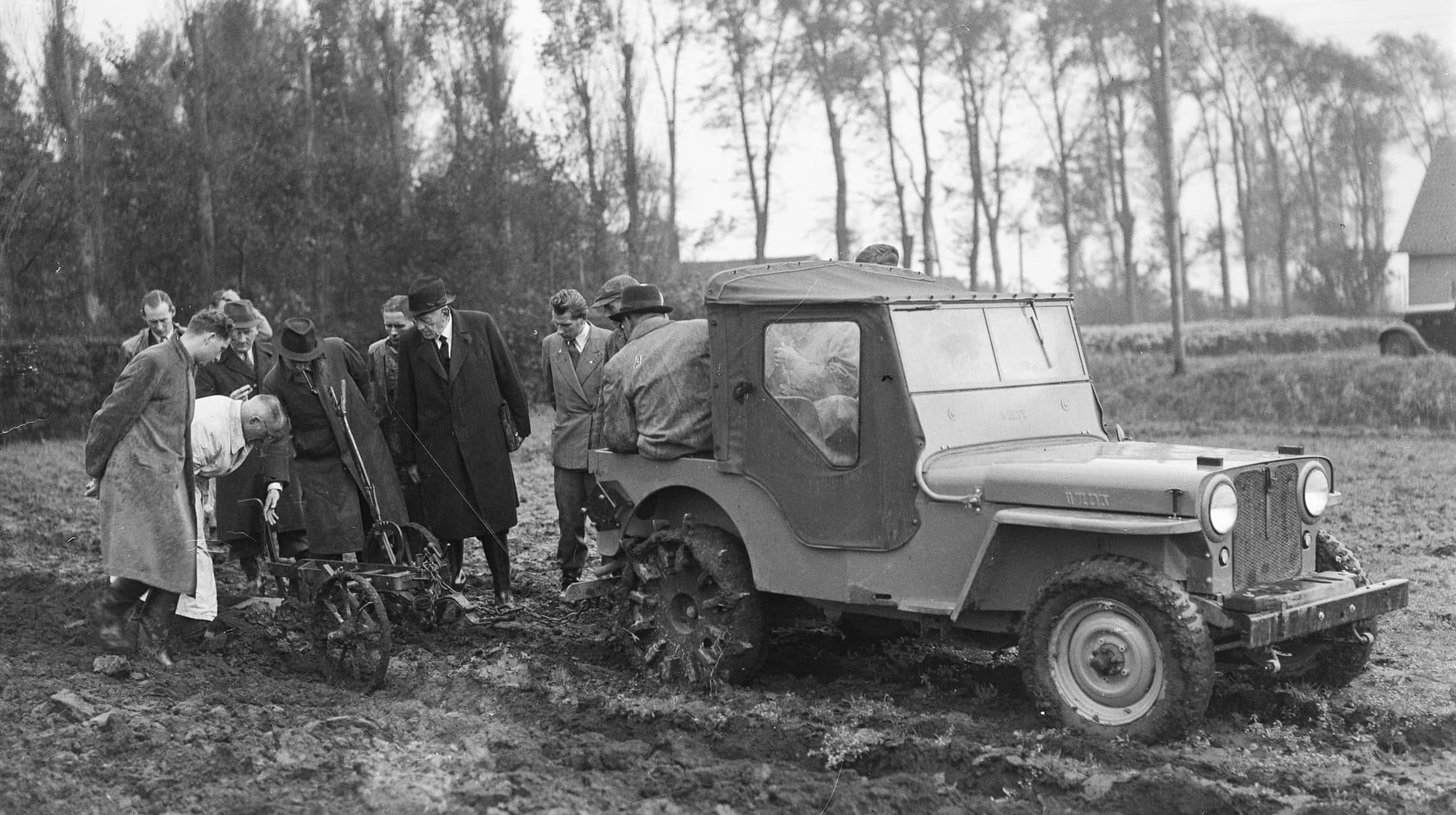 1946 年荷蘭一部 Willys Jeep 在泥地中連接農業機具,旁有多人觀察