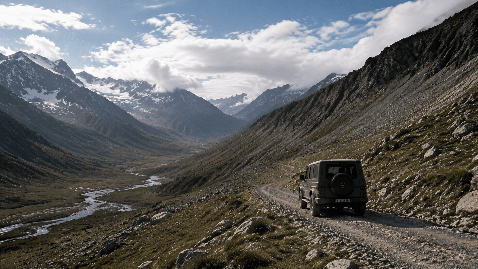 Mercedes G-Class 沿高山河谷中的碎石路駛向遠方,車輛融入遼闊山地